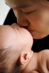A shot of an asian mother kissing her cute baby boy