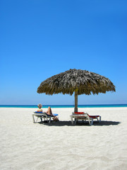 woman relaxing on a lounger reading a book at a tropical beach