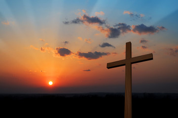 Wooden cross at sunset with colorful clouds