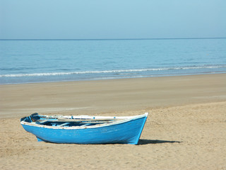 Une barque bleue de pêcheur échouée sur une plage