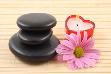 Fototapeta na wymiar stack of pebbles with candles and flower - aromatherapy