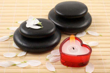 Fototapeta na wymiar stack of pebbles with candles and flower - aromatherapy