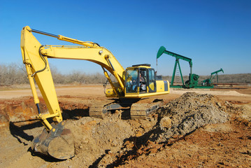 Excavator is doing dirt work for an oil well site.