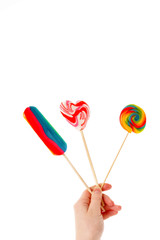 Hand holding colorful lollipops isolated over white background