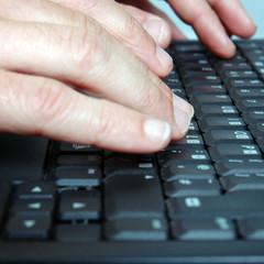 Closeup of hands typing on a laptop keyboard. 
