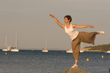 Woman making a exercise of balance at the seaside