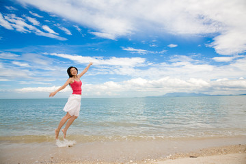 Fototapeta na wymiar red tank top woman jumping happily at the beach