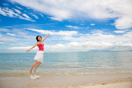 red tank top woman jumping happily at the beach