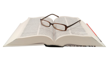 A pair of glasses on open Spanish dictionary, isolated on white.