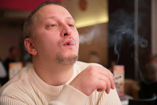 smoking man releases smoke from  mouth