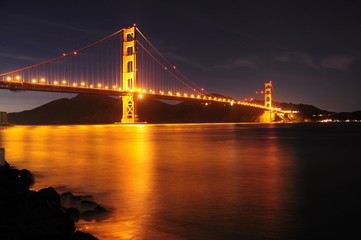 Fototapeta na wymiar Glowing Golden Gate Bridge and star trails behind