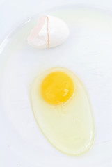 Raw Egg outside the cracked sheel on the plate .