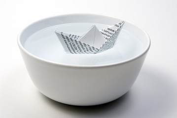 a paper boat in a bowl full of water