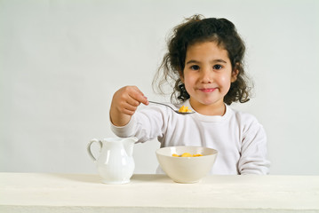 little girl holding a spoon with cereals