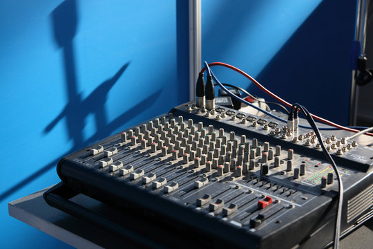 Mixing desk and shadow from microphone holders on a wall.
