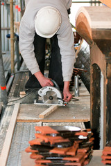 Ouvrier découpant planche de bois avec tuiles