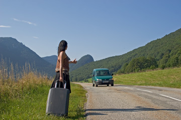 Woman on a mountain road making of hitch-hiking