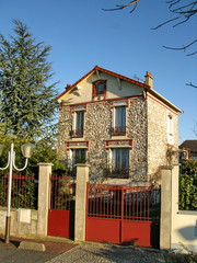 Maison de banlieue en pierre avec grille en fer rouge. France.