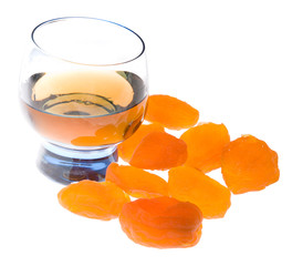 Glass of cognac and apricots on white