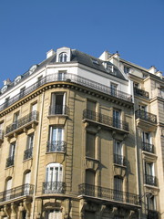 Immeuble en pierre, coin rond, fenêtre ouverte, Paris.