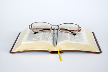 Open bible with folded reading glasses