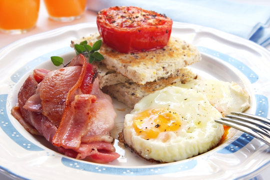 Breakfast of bacon and eggs, with grilled tomato