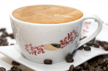 Cup of coffee and grains over white