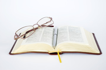 bible with a pair of spectacles and a pen