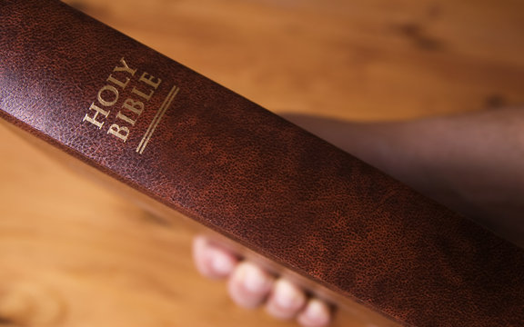 An image of a man's hand holding The Holy Bible.