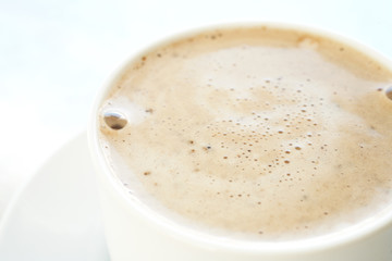 Fresh foamy cafe latte in white coffee cup on a silver 