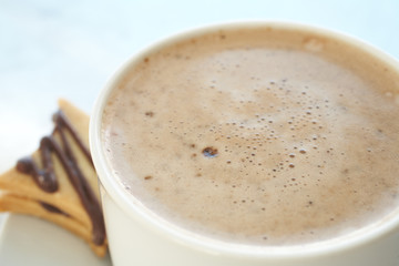 Fresh foamy cafe latte in white coffee cup on a silver