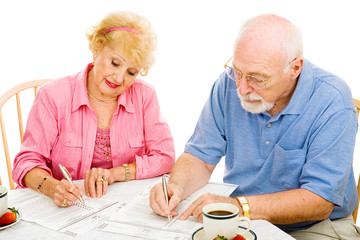 Senior couple filling out absentee ballots at home.  Isolated 