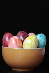 uova colorate in ciotola arancione con sfondo nero 6