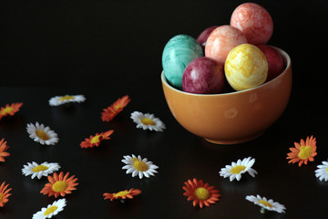 uova colorate e fiori bianchi e arancioni su fondo nero 2