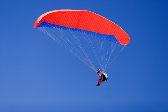 a paraplane flying high up in the deep blue sky