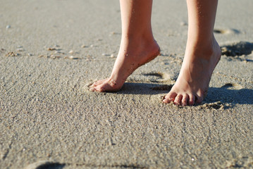Fototapeta na wymiar girl's bare foot is on the beach