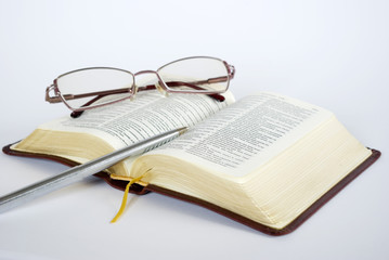 Open bible with folded reading glasses