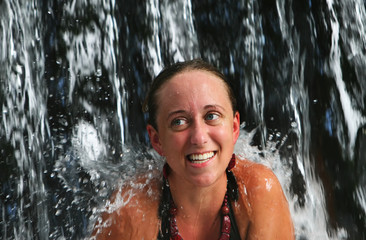A young woman under a waterfall at a five star spa