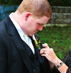 A mother pins a boutonniere on her sons jacket