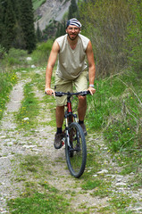 Fototapeta premium Mountain biker on old rural road in spring mountain