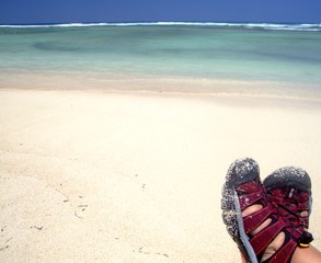 Obraz premium Person wearing red sandals enjoying sandy beach
