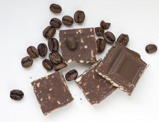 Pieces of chocolate and coffee beans on light background