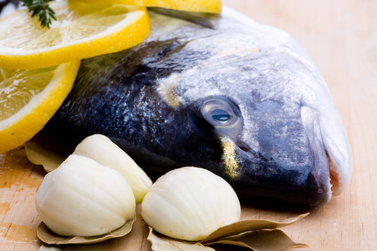 Roher Fisch mit Knoblauch, Lorbeerblätter und Zitrone