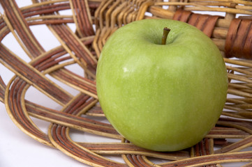 Beautiful green apple on a background of a wum vase.