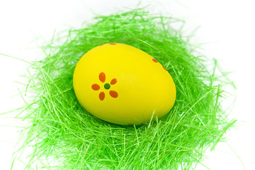 One yellow easter egg with green grass isolated on white