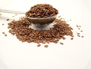 Whole flax seed overflowing a measuring spoon