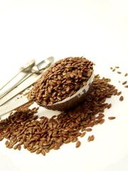 Angled image of whole flax seed overflowing a measuring spoon