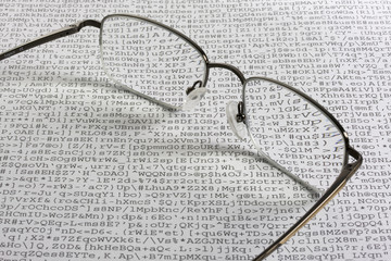 Reading glasses against meaningless text - computer gibberish - obrazy, fototapety, plakaty
