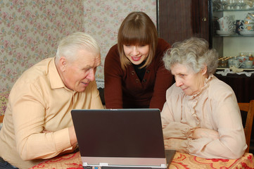 grandparents and granddaughter looking to the laptop