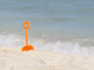 Fototapeta na wymiar red plastic spade on the sunny tropical beach